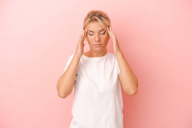 Genç Rus kadın pembe arka planda izole edilmiş tapınaklara dokunuyor ve baş ağrısı çekiyor..