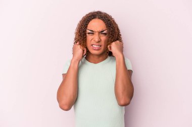 Genç Latin transseksüel kadın pembe arka planda izole edilmiş kulakları elleriyle kapatıyor..