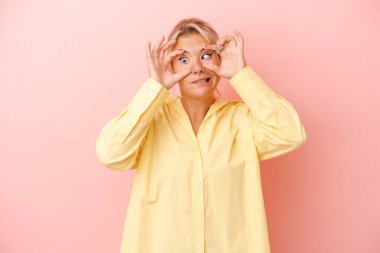 Pembe arka planda izole edilmiş genç bir Rus kadın bir başarı fırsatı bulmak için gözlerini açık tutuyor..