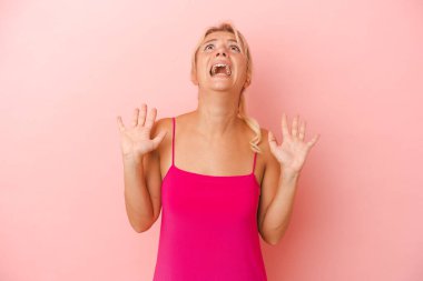 Pembe arka planda izole edilmiş genç Rus kadın gökyüzüne haykırıyor, yukarı bakıyor, hayal kırıklığına uğramış..