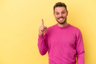 Sarı arka planda izole genç beyaz adam parmak ile bir numara gösteriyor.