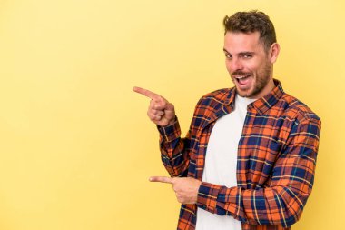 Sarı arka planda izole edilmiş genç beyaz adam işaret parmağıyla fotokopi alanını işaret ederek heyecan ve arzusunu ifade ediyor..