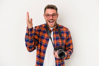 Beyaz arka planda izole genç beyaz fotoğrafçı hoş bir sürpriz alıyor, heyecanlı ve el kaldırıyor..