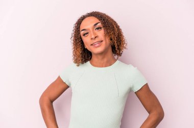 Young latin transsexual woman isolated on pink background confident keeping hands on hips. clipart