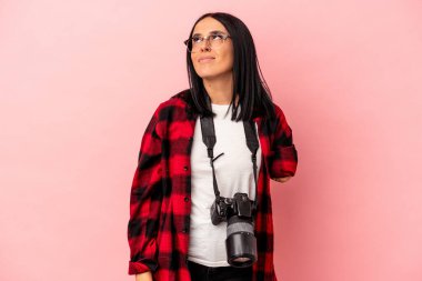 Tek kolu pembe arka planda izole edilmiş, hedeflerine ve amaçlarına ulaşma hayali kuran Kafkasyalı genç fotoğrafçı kadın.