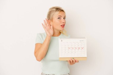 Beyaz arka planda izole edilmiş bir takvim tutan genç Rus kadın bir dedikoduyu dinlemeye çalışıyor..