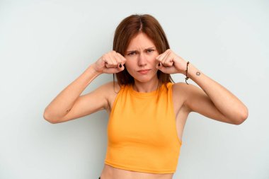 Mavi arka planda izole edilmiş genç bir İngiliz kadın bir tartışma yüzünden yumruk, öfke, kavga ve boks atıyor..