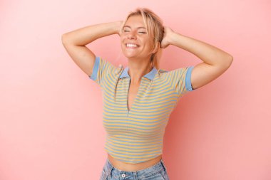 Pembe arka planda izole edilmiş genç bir Rus kadın kendini güvende hissediyor, elleri başının arkasında..