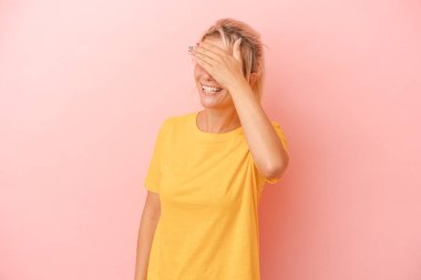 Pembe arka planda izole edilmiş genç bir Rus kadın elleriyle gözlerini kapatıyor, büyük bir gülümsemeyle bir sürpriz bekliyor..