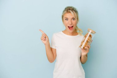 Elinde mavi arka planda izole edilmiş kurabiyeler tutan genç Rus kadın...