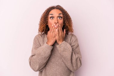 Pembe arka planda izole edilmiş genç Latin transseksüel kadın elleriyle ağzını kapatırken şok oldu..