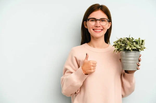 Jong Engels Vrouw Houden Een Plant Geïsoleerd Blauwe Achtergrond Glimlachen — Stockfoto
