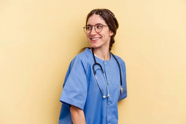 Jonge Verpleegster Kaukasische Vrouw Geïsoleerd Gele Achtergrond Kijkt Opzij Glimlachend — Stockfoto
