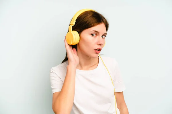 Młoda Angielka Słuchająca Muzyki Odizolowanej Niebieskim Tle Próbująca Słuchać Plotek — Zdjęcie stockowe