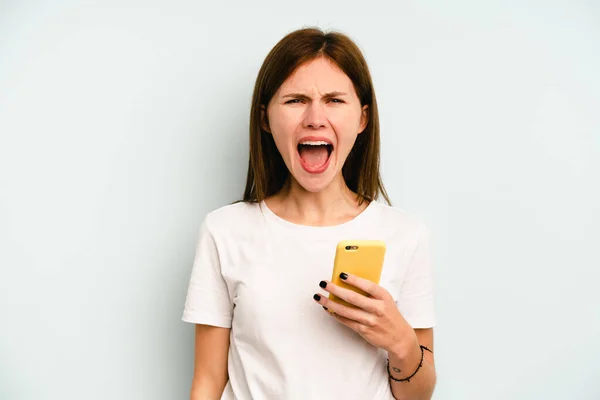 Молодая Английская Женщина Держит Мобильный Телефон Изолирован Синем Фоне Кричать — стоковое фото