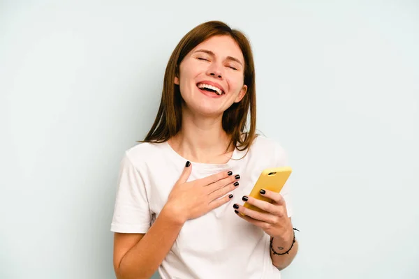 Young English Woman Holding Mobile Phone Isolated Blue Background Laughs — Stock Photo, Image
