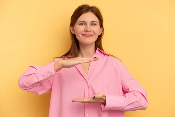 Jovem Inglesa Isolada Fundo Amarelo Segurando Algo Com Ambas Mãos — Fotografia de Stock