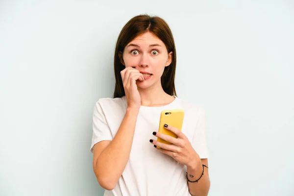 Jovem Inglesa Segurando Celular Isolado Fundo Azul Mordendo Unhas Nervoso — Fotografia de Stock