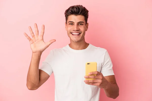 Młody Biały Mężczyzna Trzymając Telefon Komórkowy Odizolowany Różowy Tło Uśmiech — Zdjęcie stockowe