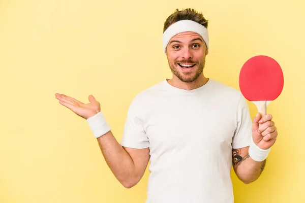 Jovem Caucasiano Segurando Raquete Ping Pong Isolado Fundo Amarelo Mostrando — Fotografia de Stock
