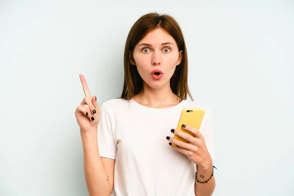 Jovem Inglesa Segurando Celular Isolado Fundo Azul Tendo Alguma Grande — Fotografia de Stock