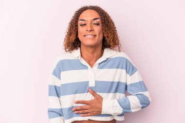 Genç Latin transseksüel kadın pembe arka planda izole edilmiş karnına dokunuyor, nazikçe gülümsüyor, yemek yiyor ve tatmin oluyor..