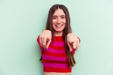 Yeşil arka planda izole edilmiş genç beyaz kadın. Önü gösteren neşeli gülümsemeler..