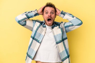 Sarı arka planda izole edilmiş genç beyaz bir adam çığlık atıyor, çok heyecanlı, tutkulu, bir şeyden memnun..