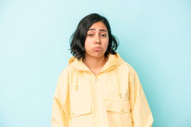 Mavi arka planda izole edilmiş genç Latin kadın üzgün, ciddi yüz, mutsuz ve hoşnutsuz hissediyor.