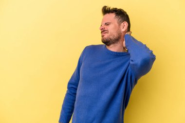 Sarı arka planda izole edilmiş genç beyaz adam yorgun ve uykulu bir şekilde ellerini başının üstünde tutuyor..