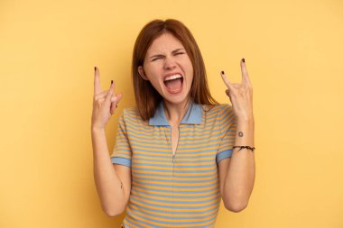 Sarı arka planda izole edilmiş genç İngiliz kadın boynuzlarını devrim konsepti olarak gösteriyor..