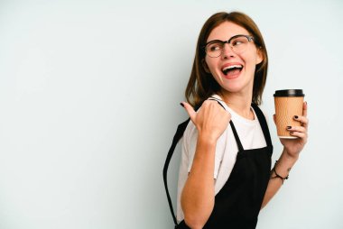 Restoran garsonu elinde kahve tutan kadın mavi arka planda izole edilmiş, baş parmak uzakta, gülen ve kaygısız..