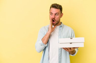 Sarı arka planda izole edilmiş pizzalar tutan genç beyaz adam gizli bir sıcak fren haberinin olduğunu söylüyor.