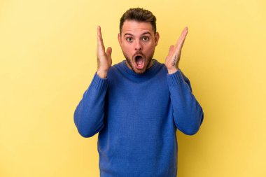 Sarı arka planda izole edilmiş genç beyaz adam şaşırdı ve şok oldu..