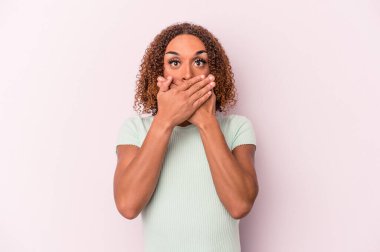 Pembe arka planda izole edilmiş genç Latin transseksüel kadın elleriyle ağzını kapatırken şok oldu..