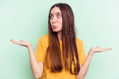 Yeşil arka planda izole edilmiş beyaz bir kadın. Kafası karışmış ve omuz silkiyor. Kopya alanını tutmak için..