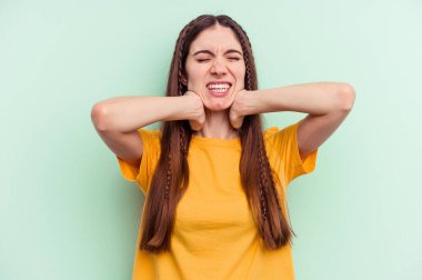 Genç, beyaz bir kadın yeşil arka planda izole edilmiş, sabit yaşam tarzından dolayı boyun ağrısı çekiyor..