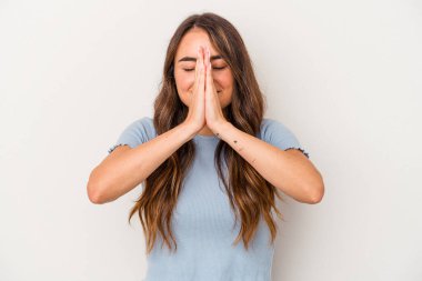 Beyaz arka planda izole edilmiş genç beyaz bir kadın el ele dua ederken, kendine güveniyor..