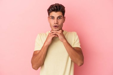 Pembe arka planda izole edilmiş genç beyaz adam şans için dua ediyor, hayrete düşüyor ve ağzını açıp önüne bakıyor..