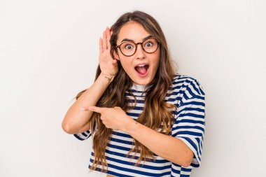 Beyaz arka planda izole edilmiş genç beyaz kadın bir dedikoduyu dinlemeye çalışıyor..