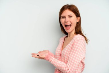 Mavi arka planda izole edilmiş genç bir İngiliz kadın avucunun üzerinde bir kopya alanı tutuyor..