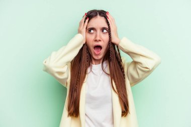 Kafkasyalı genç bir kadın yeşil arka planda izole edilmiş kulakları kulaklarıyla kapatıyor çok fazla ses duymamaya çalışıyor..