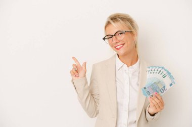 Beyaz arka planda izole edilmiş banknotlar tutan genç Rus kadın gülümsüyor ve boş alanda bir şeyler gösteriyor..