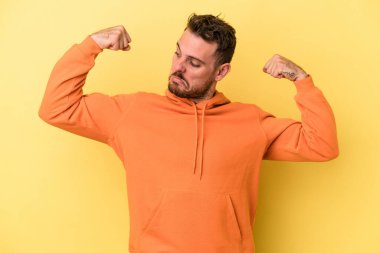 Sarı arka planda izole edilmiş genç beyaz adam güçlü bir hareket sergiliyor, kadınsı gücün sembolü.