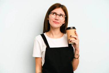 Lokantadaki garson kadın mavi arka planda izole edilmiş bir kahve tutuyor. Amaçlarına ve amaçlarına ulaşma hayalleri kuruyor.