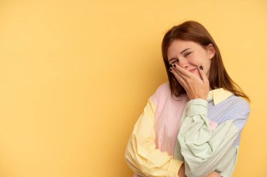 Sarı arka planda izole edilmiş genç İngiliz kadın güler, kaygısız, doğal duygular.