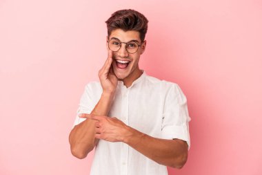 Pembe arka planda izole edilmiş genç beyaz bir adam bir dedikodu söylüyor, bir haber sunuyor..