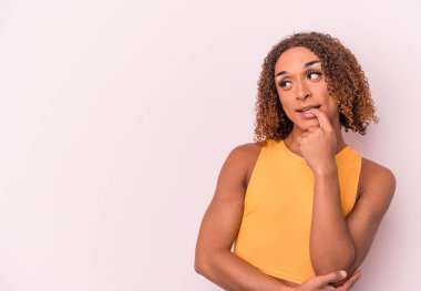 Pembe arka planda izole edilmiş genç Latin transseksüel kadın rahatça fotokopi odasına bakan bir şey düşünüyor..