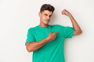 Beyaz arka planda izole edilmiş genç beyaz bir adam güçlü bir hareket gösteriyor, kollarıyla, kadınsı gücün sembolü.