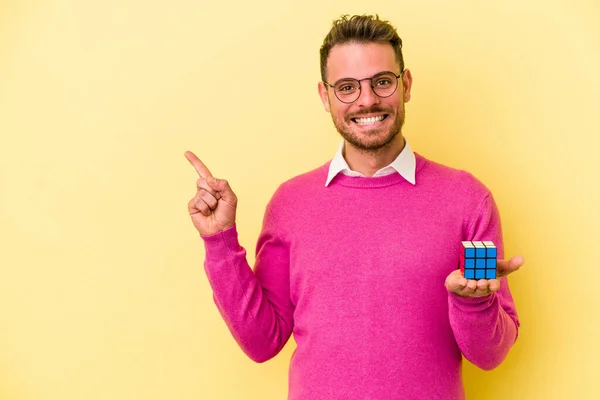 Mladý Běloch Držící Rubikovu Kostku Izolovanou Žlutém Pozadí Usmívající Ukazující — Stock fotografie